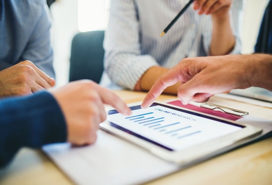 Mehrere Personen analysieren digitale Daten auf einem Tablet – Teammeeting zu IT- und Digitalisierungslösungen bei der ISO-Gruppe.